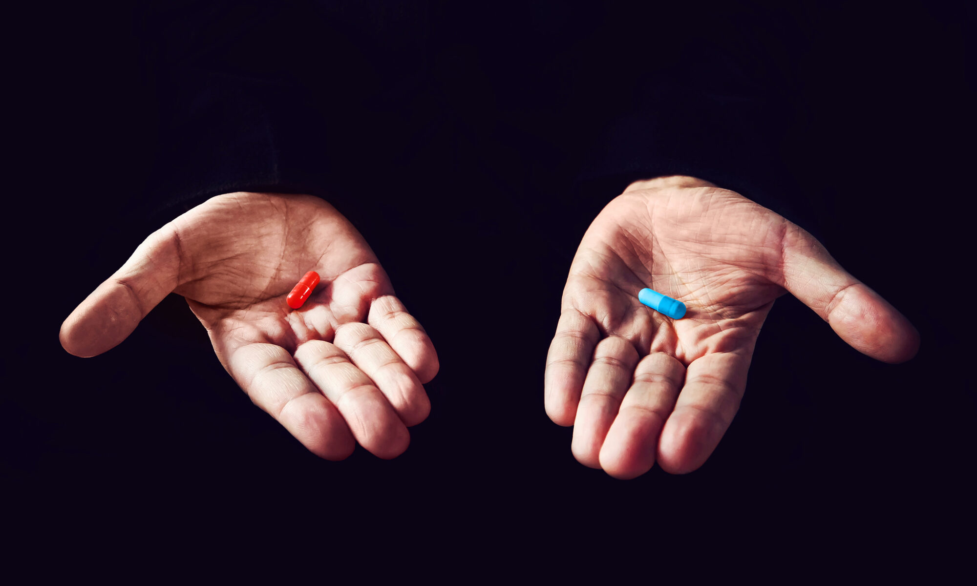 Image of two hands holding different color pills